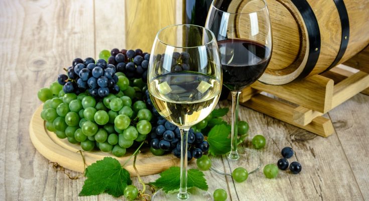 Ein Weißwein und ein Rotwein vor Weintrauben.